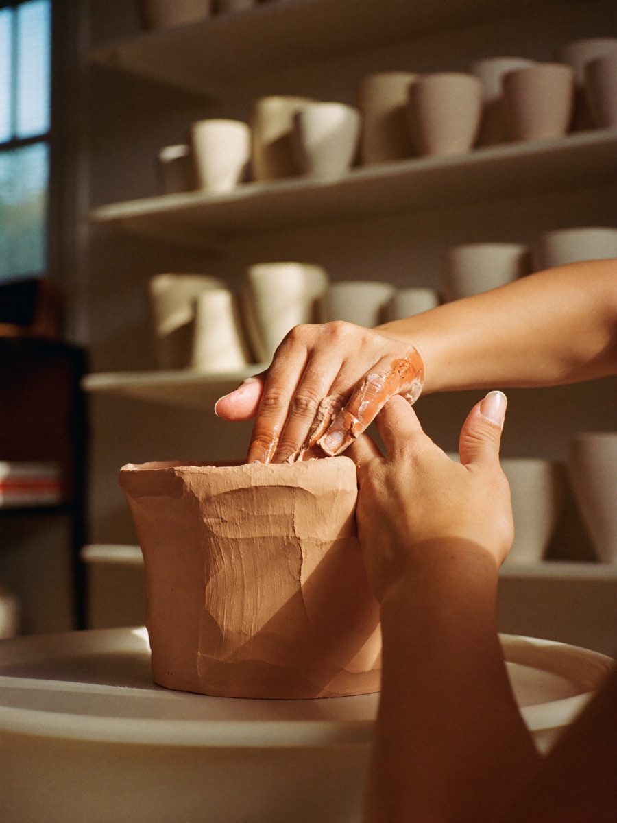 Hands shaping a terracotta bowl on a pottery wheel