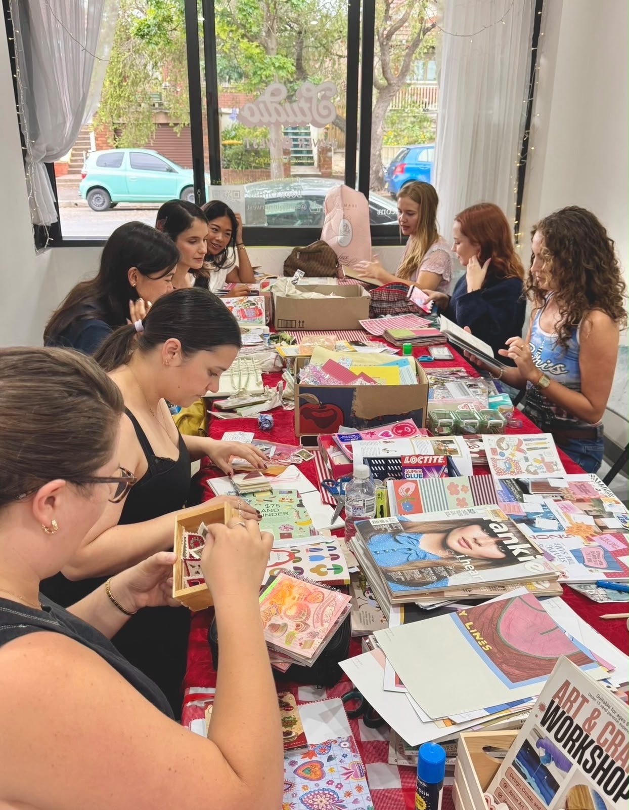 A packed collage workshop at Studio Inner West, students crafting along a long red table