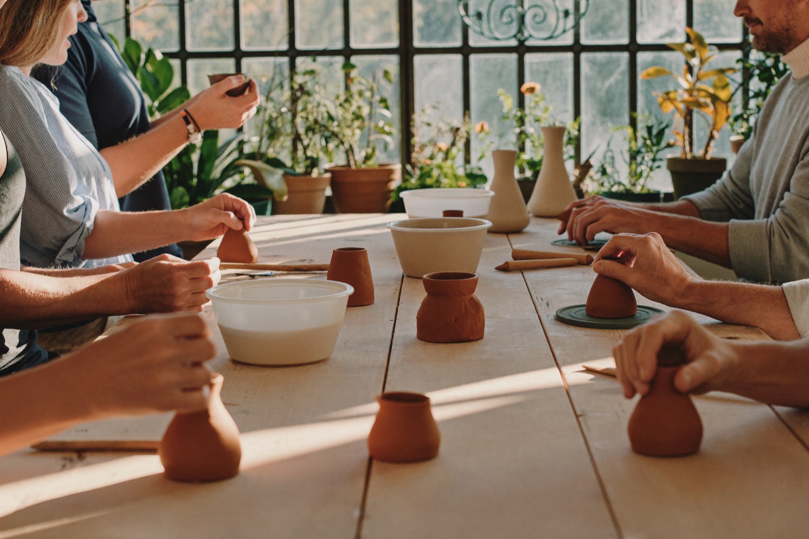 A workshop table of people hand-building clay pieces